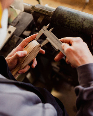 Handcrafted measurement of a wooden brush handle in the Altesse Studio workshop, showcasing precision craftsmanship.