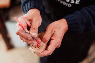 Gros plan sur le contrôle manuel du perçage des trous dans un manche de brosse en bois, première étape du travail fait-main pour la collection Prestige d’Altesse Studio.